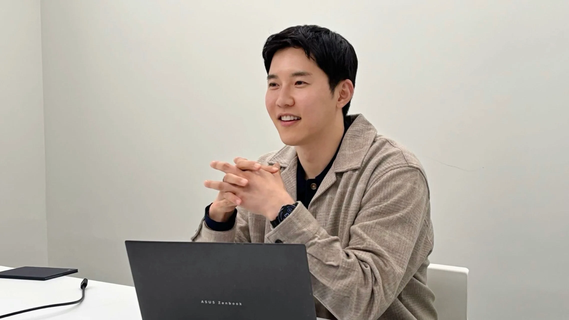 인터뷰에서 두 손을 모으고 웃으며 답하는 드코어(DECORE) 김정훈 대표
